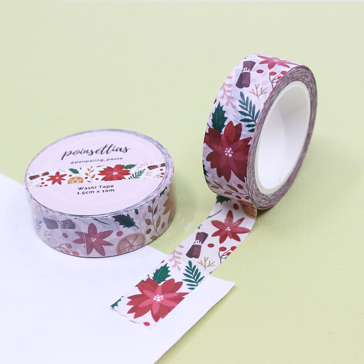 Poinsettia Washi Tape roll with red flowers, greenery, and festive accents on soft blush background.