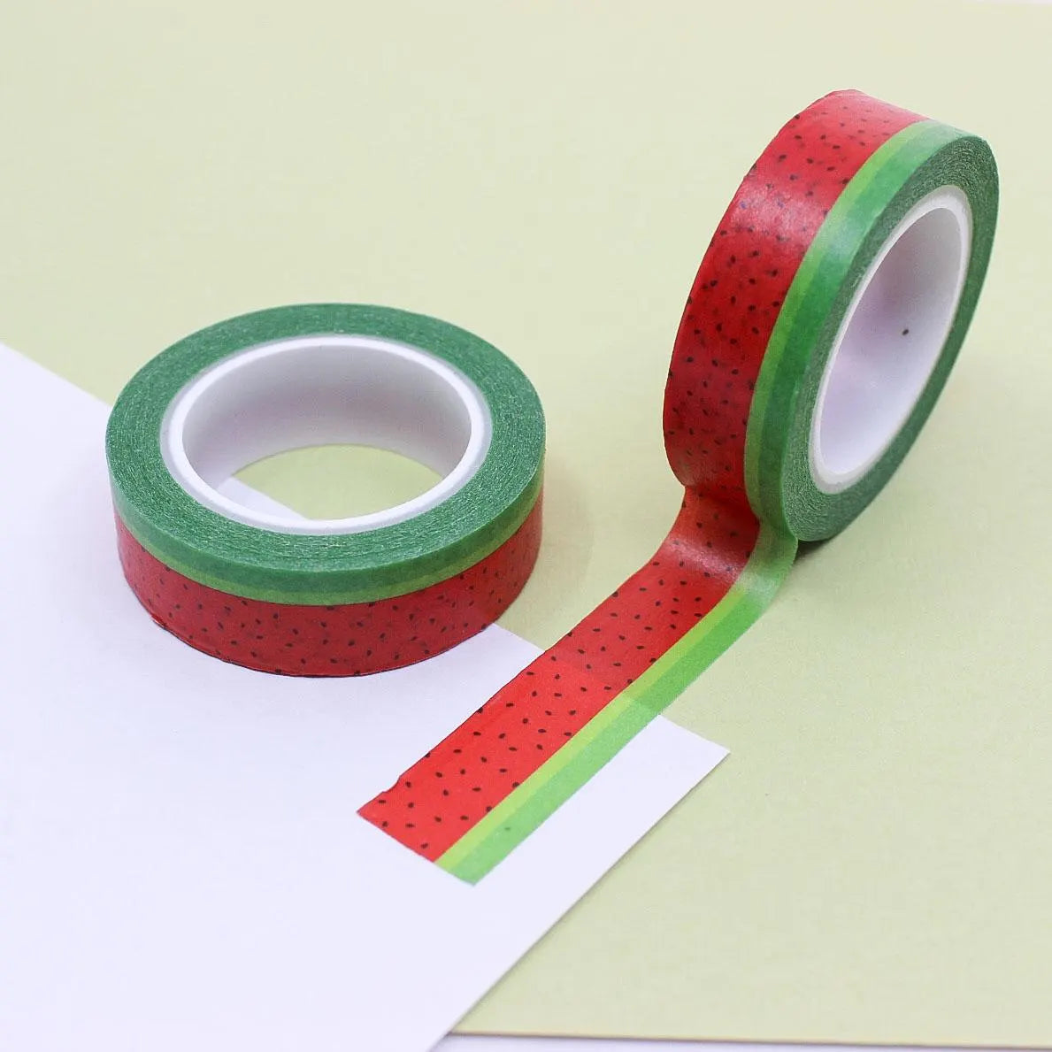 Roll of watermelon-themed washi tape with red seeds and green rind design, displayed on a white background.