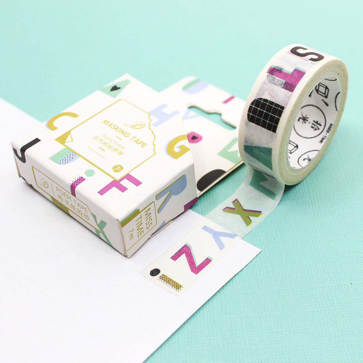 oll of colorful alphabet washi tape unrolled on a pastel surface.