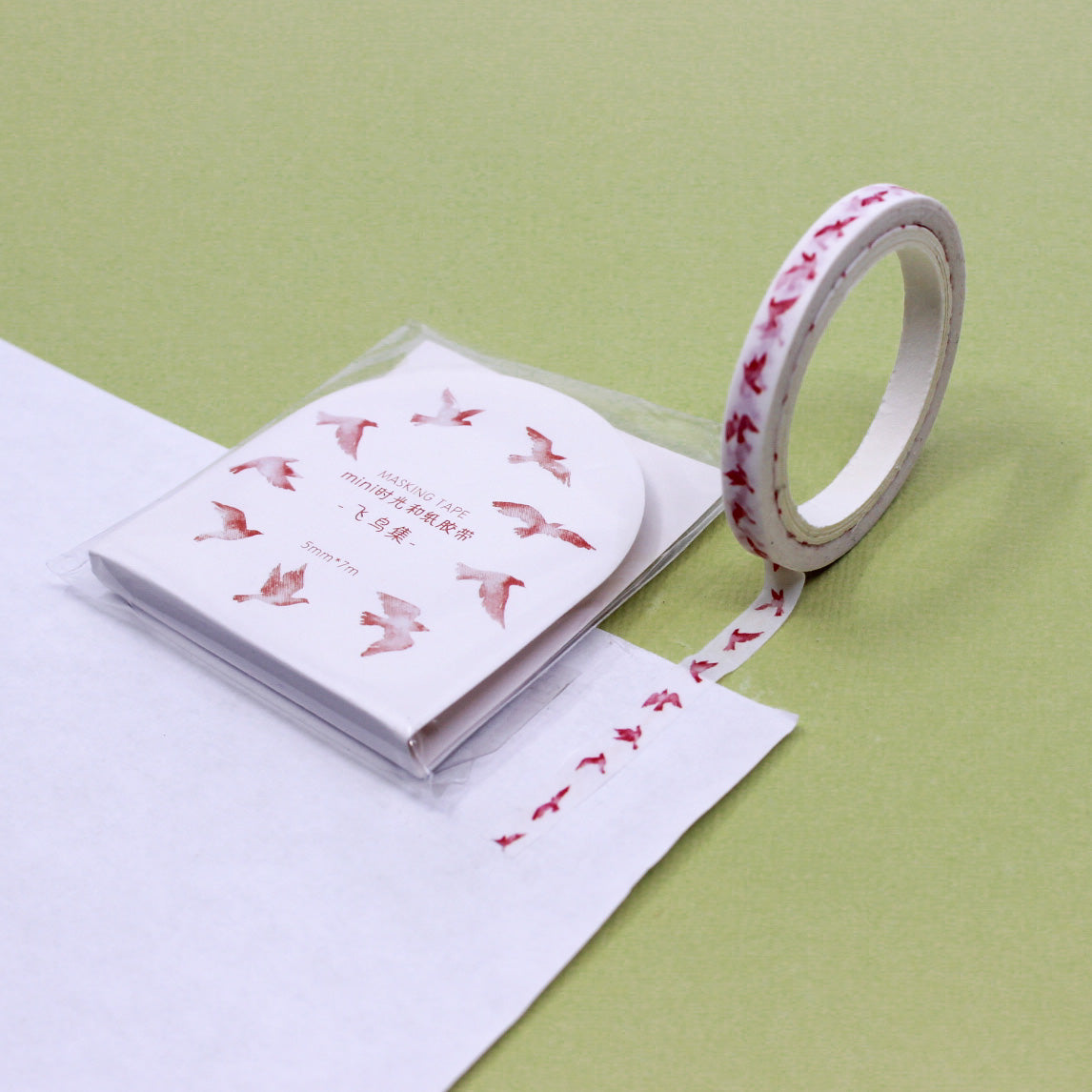 Roll of bird-themed washi tape with packaging shown in a flat lay stationery setup.