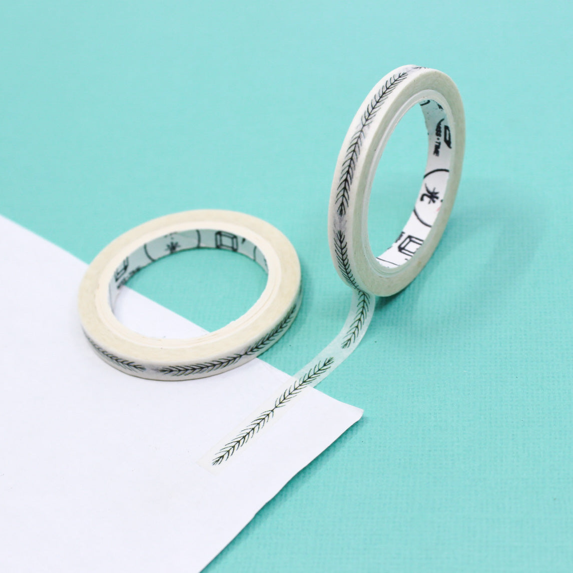 Close-up of narrow botanical leaf washi tape next to its matching packaging.