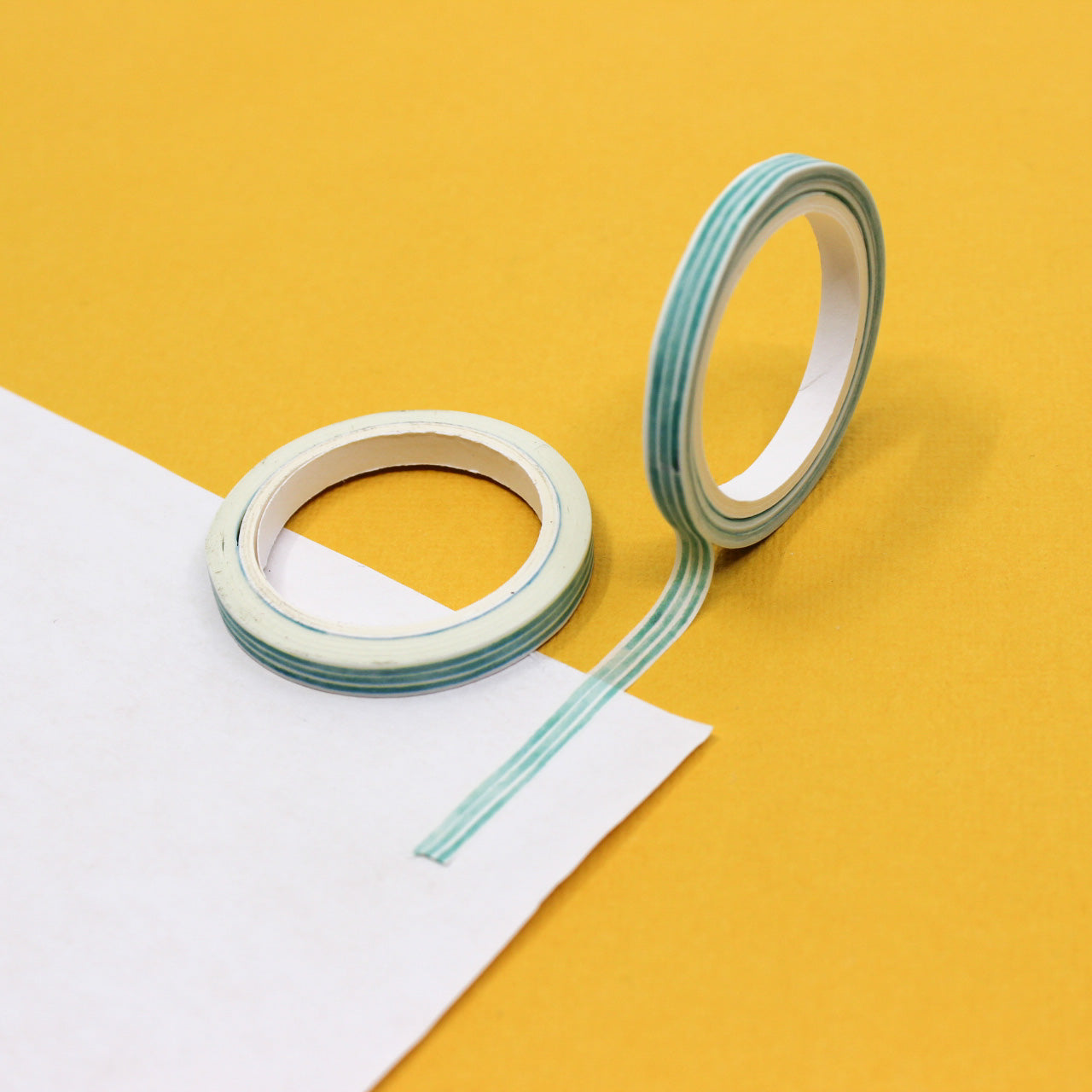 Minimalist mint striped washi tape roll photographed beside packaging.