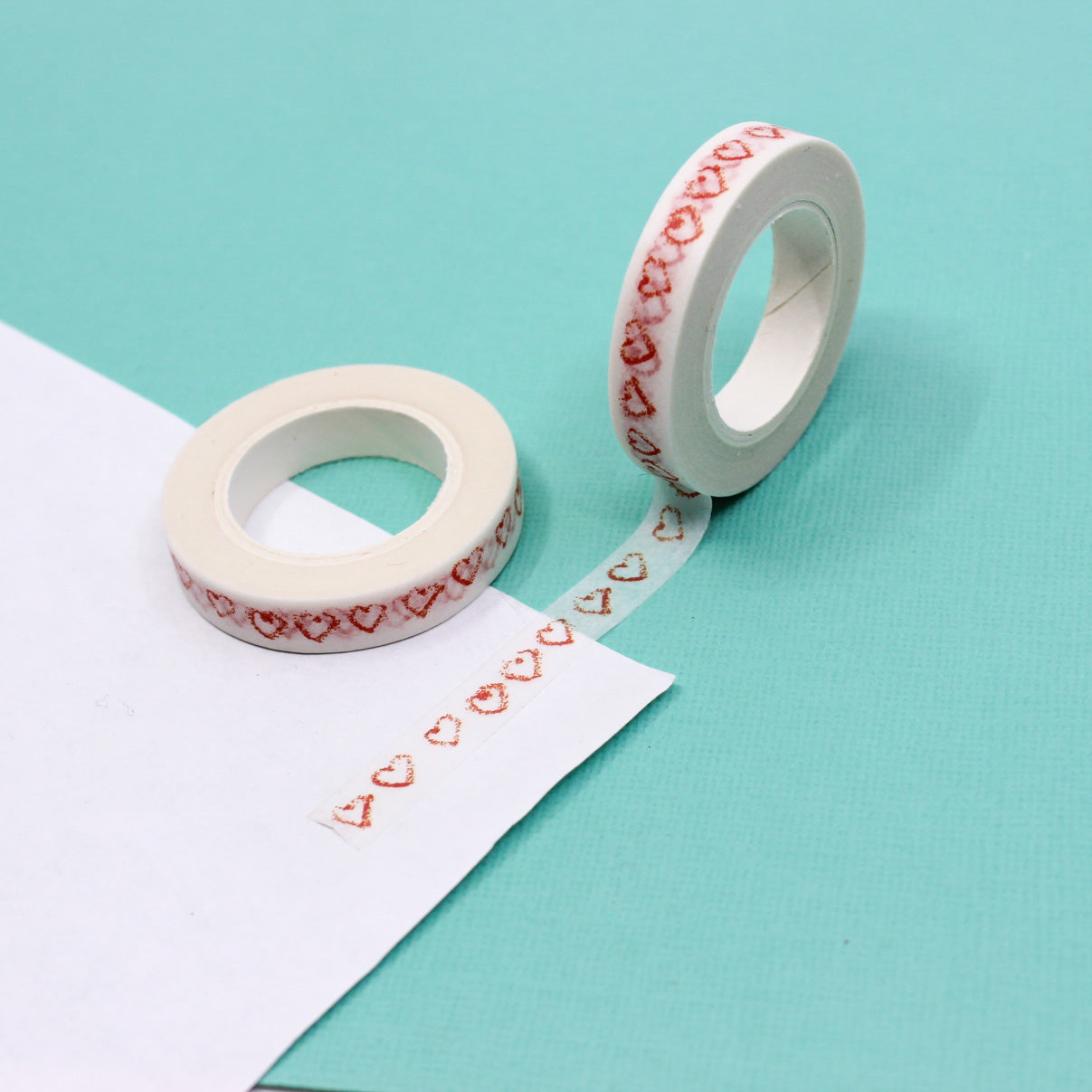 Elevate your projects with our Narrow Red Sketchy Hearts Border Washi Tape, adorned with charming and hand-drawn heart patterns. Ideal for adding a touch of playful romance to your crafts. This tape is sold at BBB Supplies Craft Shop.