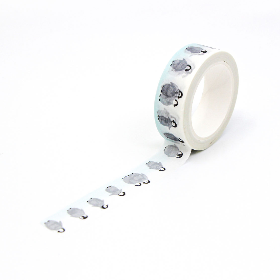 Roll of decorative tape with baby penguins waddling in a row — ideal for winter crafts and stationery.