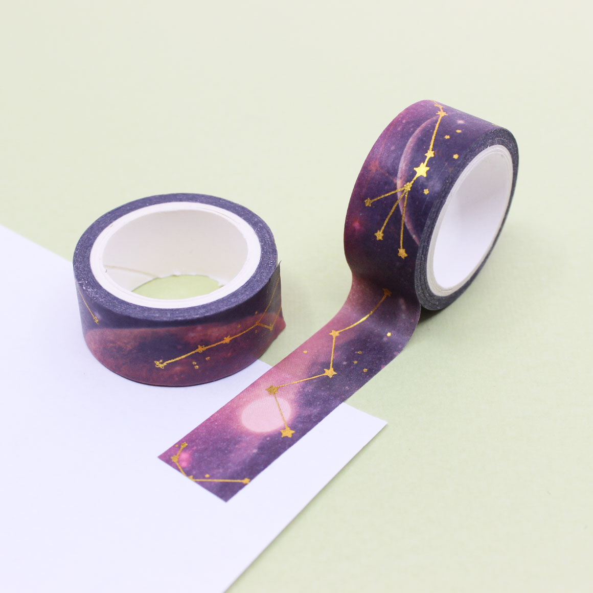 Galaxy constellation washi tape roll with gold foil stars unrolled on paper.