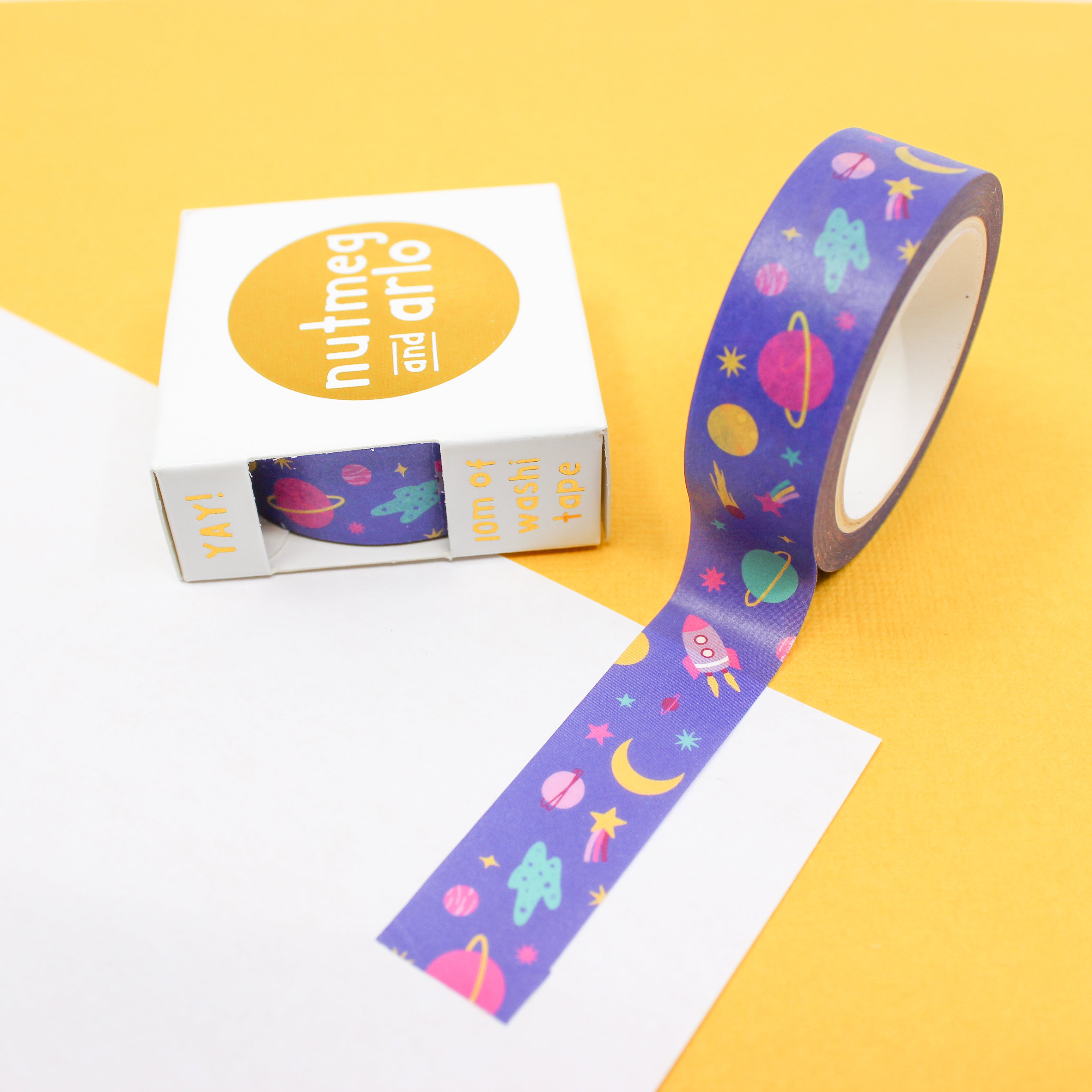 This picture is of a roll of washi tape that features outer space themed items with planets, rocket ship, comets, stars and the moon from BBB Supplies craft and journaling Supply Shop.