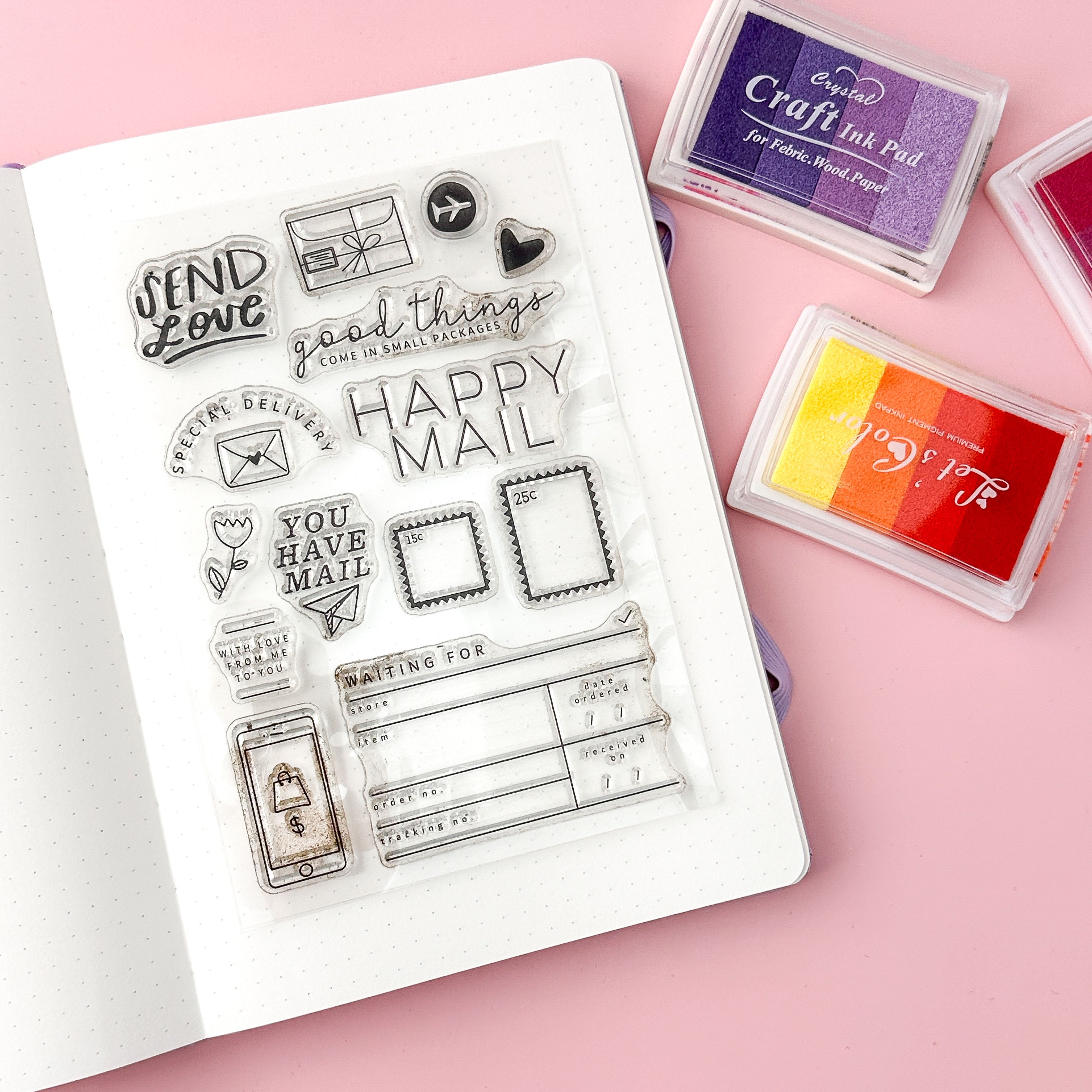 Clear stamp set with various designs that are perfect for snail mail, happy mail, or penpals on a pink background with ink pads.