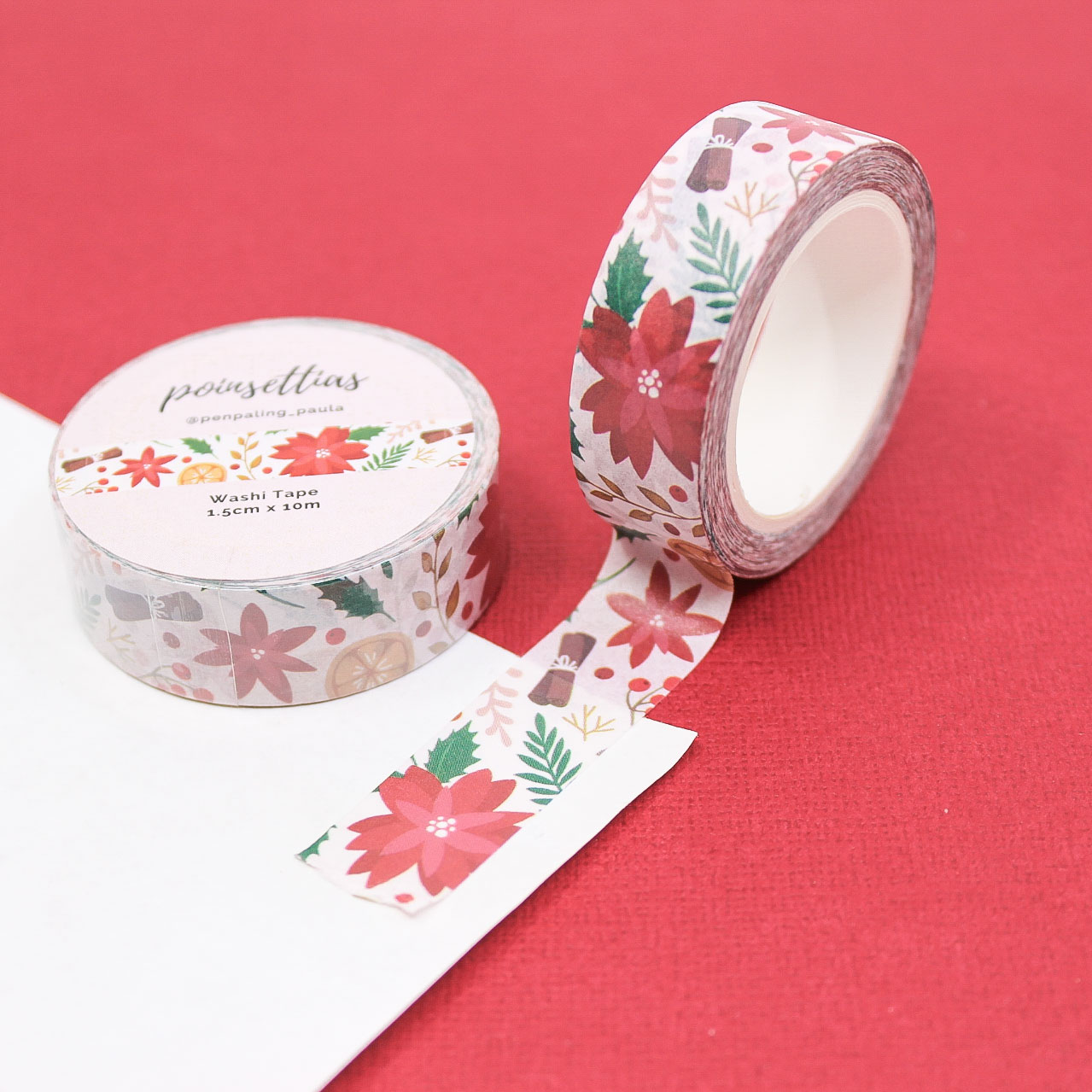 Red poinsettia and foliage patterned washi tape roll for journaling, wrapping, and holiday paper crafts.