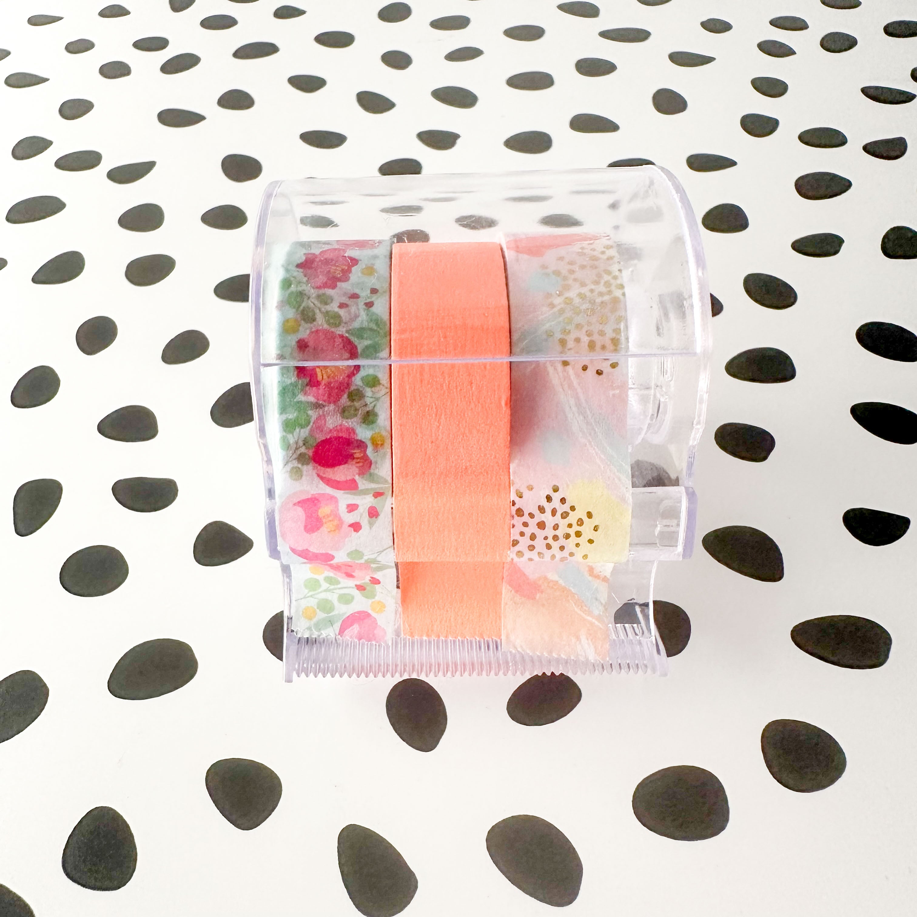 Washi tape cutter holding colorful tapes on a white desktop