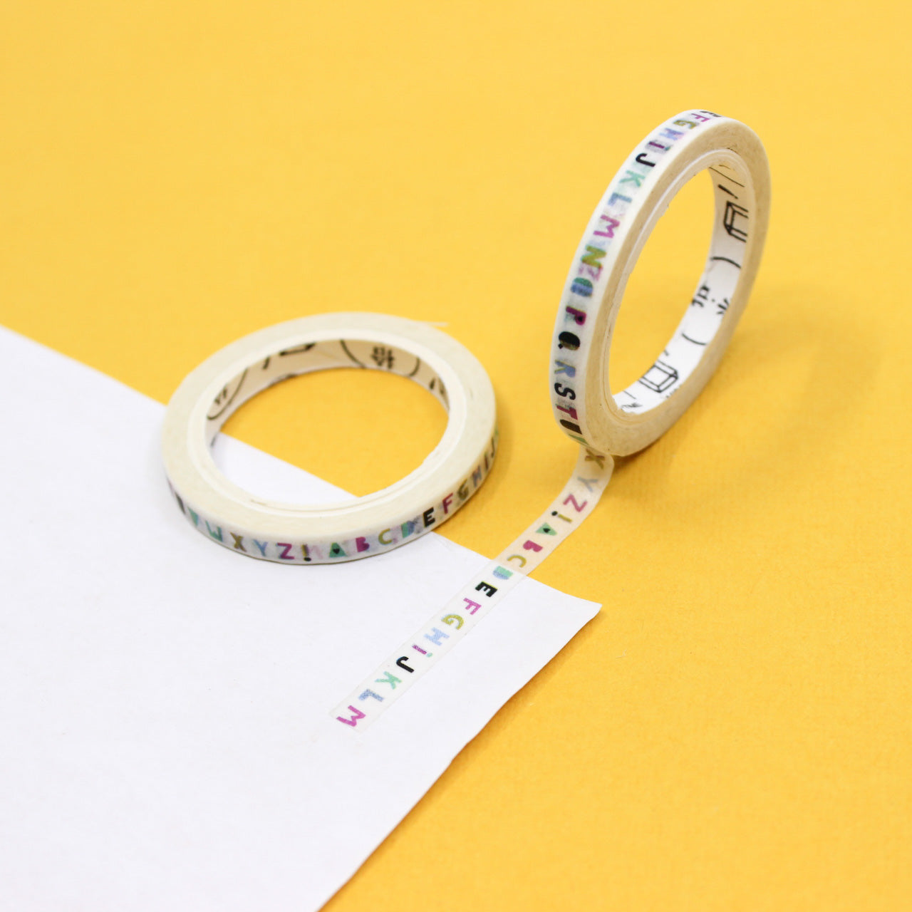 Cute mini letter washi tape roll with colorful typography pattern displayed for journaling use.