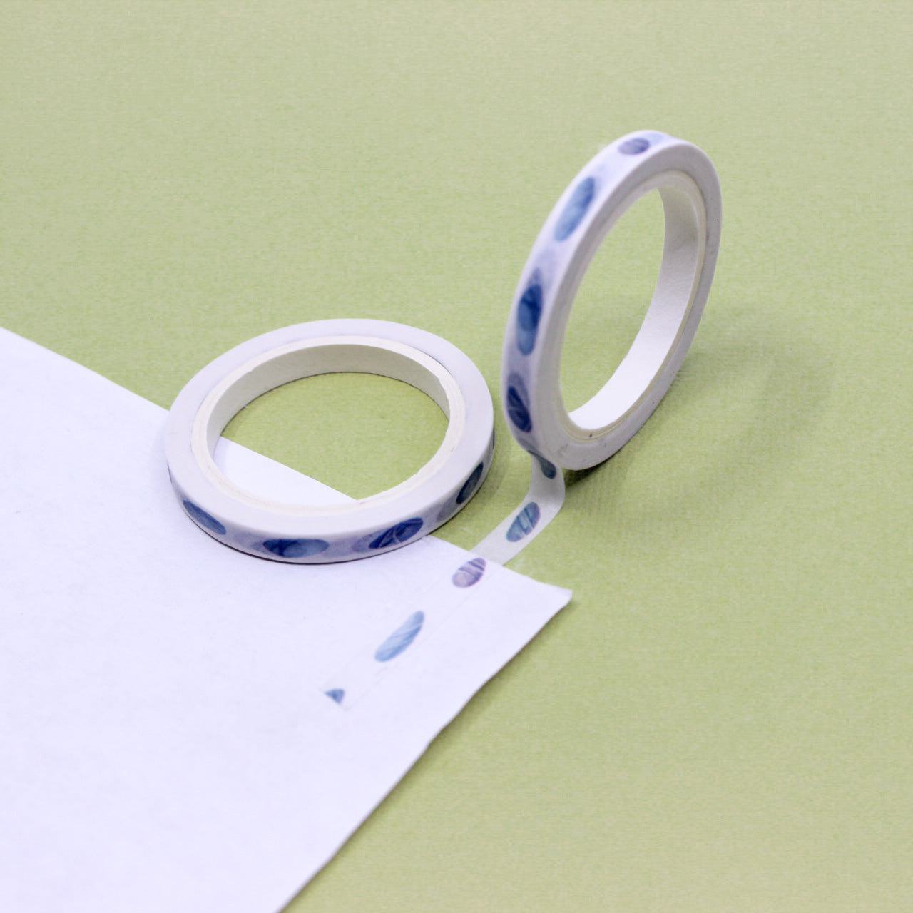 Decorative watercolor pebble washi tape unrolled in a thin border strip for journaling.