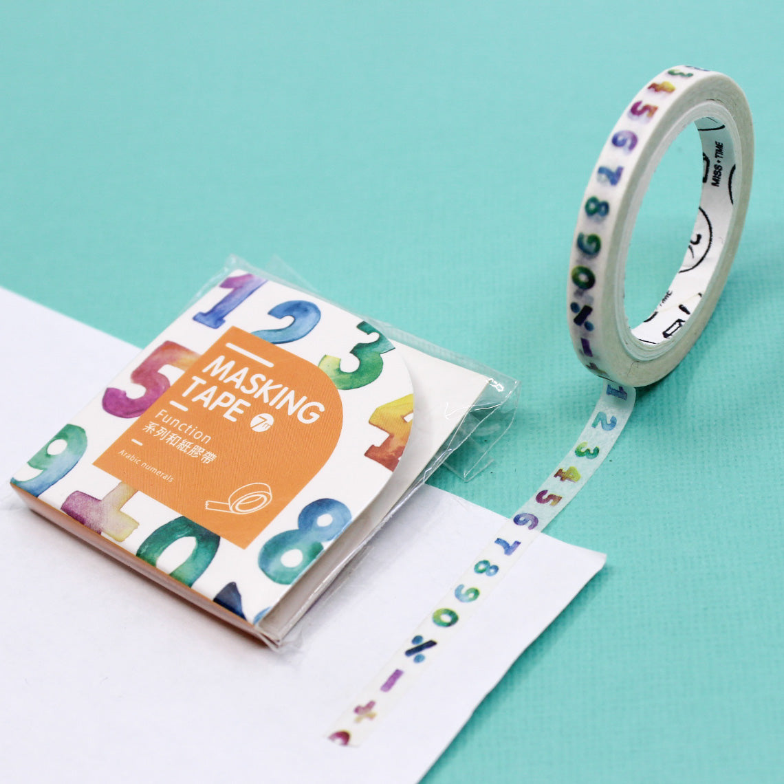 Close-up of watercolor number pattern washi tape on a teal background.