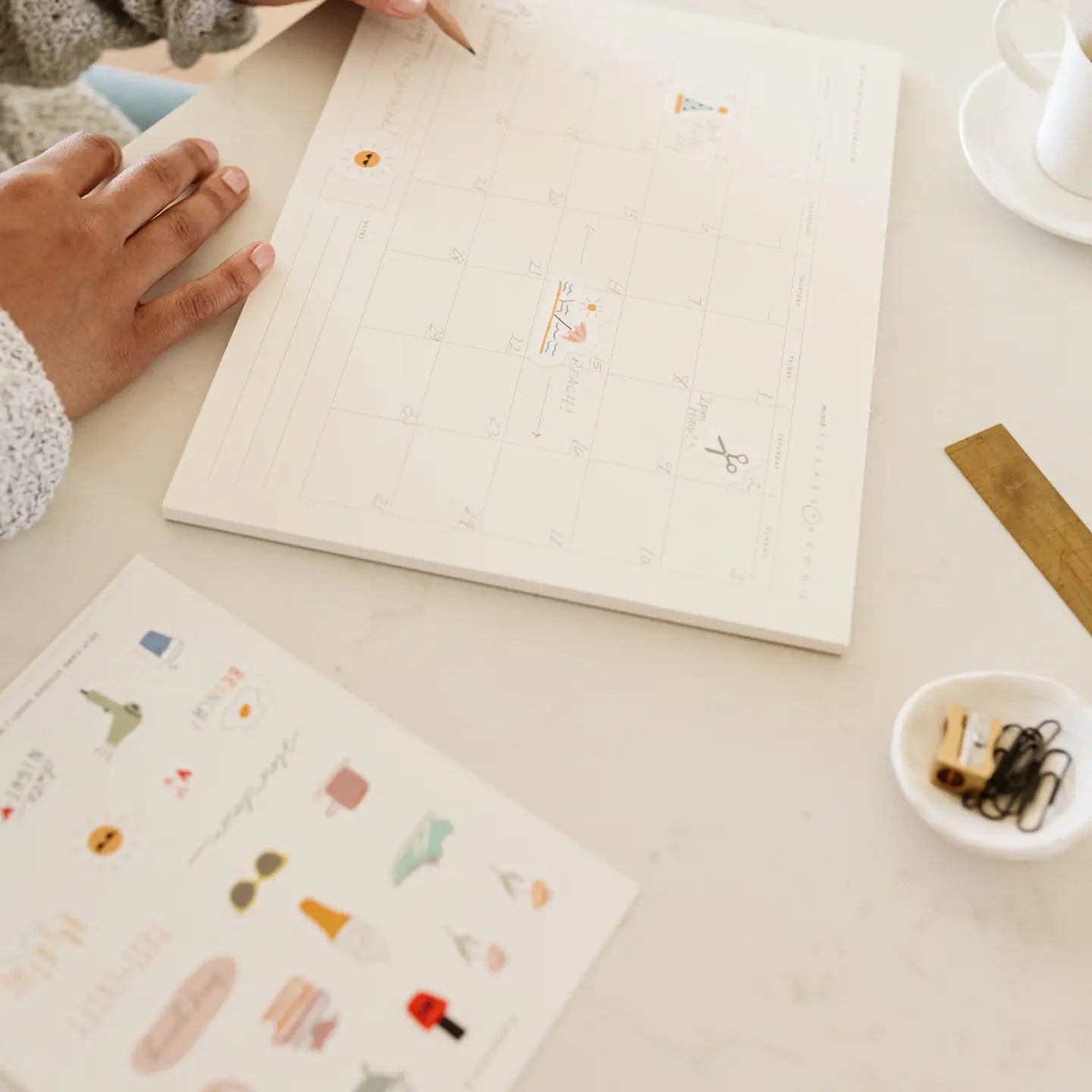 Person holding a notebook with decorative stickers on a light surface.