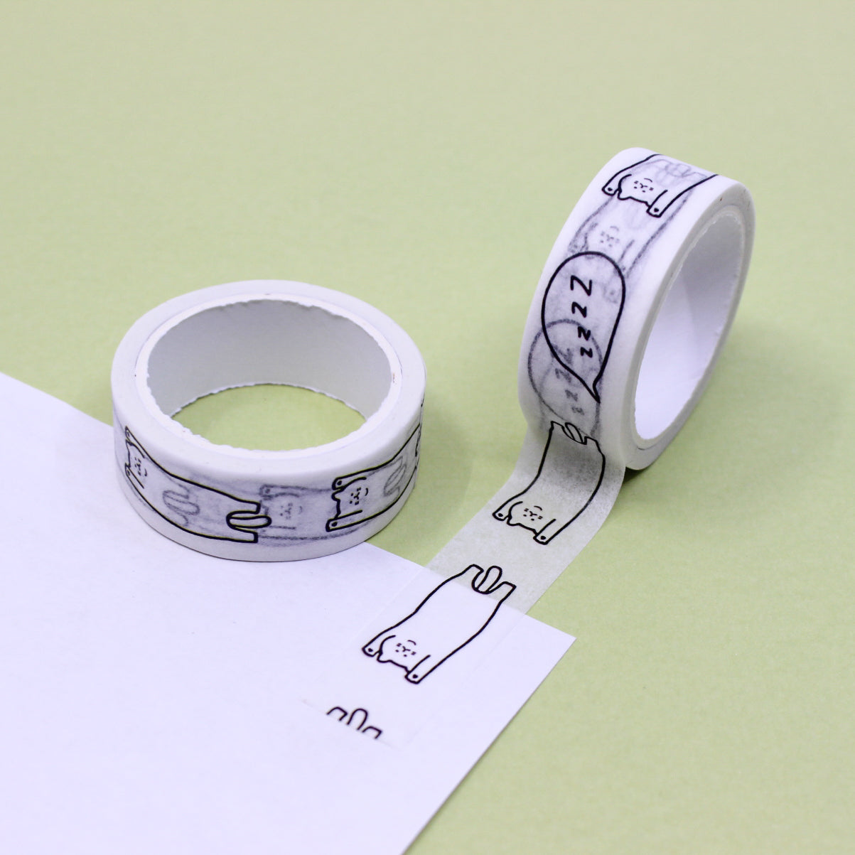 A playful and whimsical Black and White Cartoon Sleeping Cat Washi Tape. The tape features a charming design of black cats engaged in various playful activities, exuding a sense of feline mischief. This cat-themed washi tape is a must-have for cat lovers, adding a delightful touch to their creative projects. This tape is sold exclusively at BBB Supplies Craft Shop.