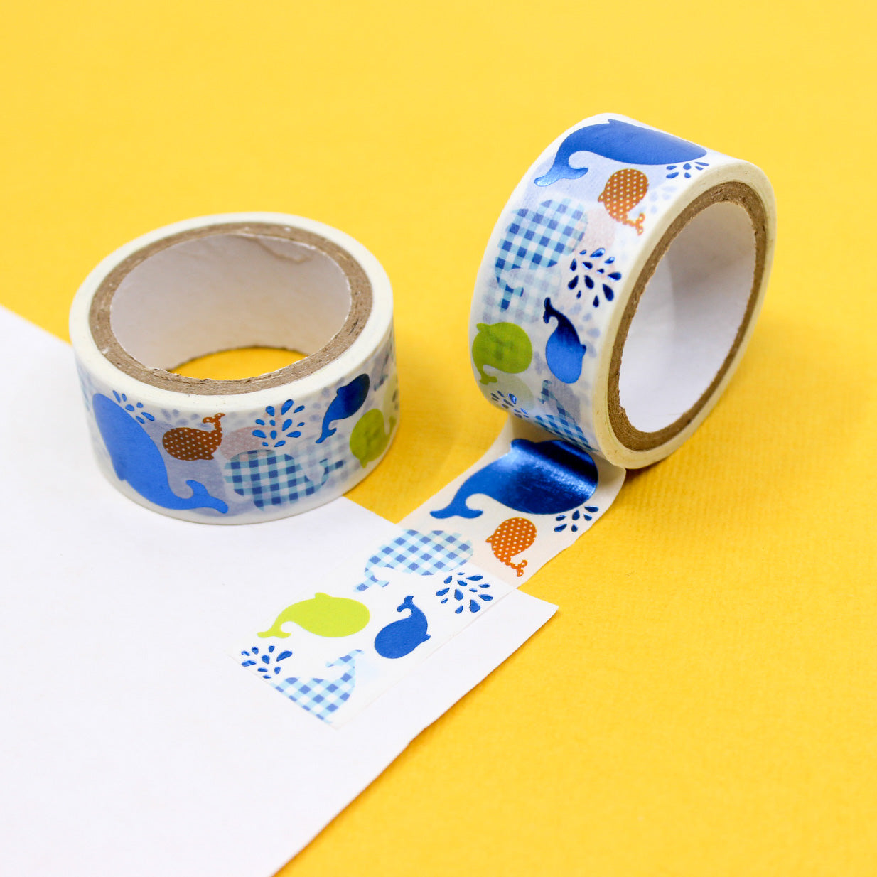 Cute whale washi tape roll with blue, green, and orange whale illustrations on white background.